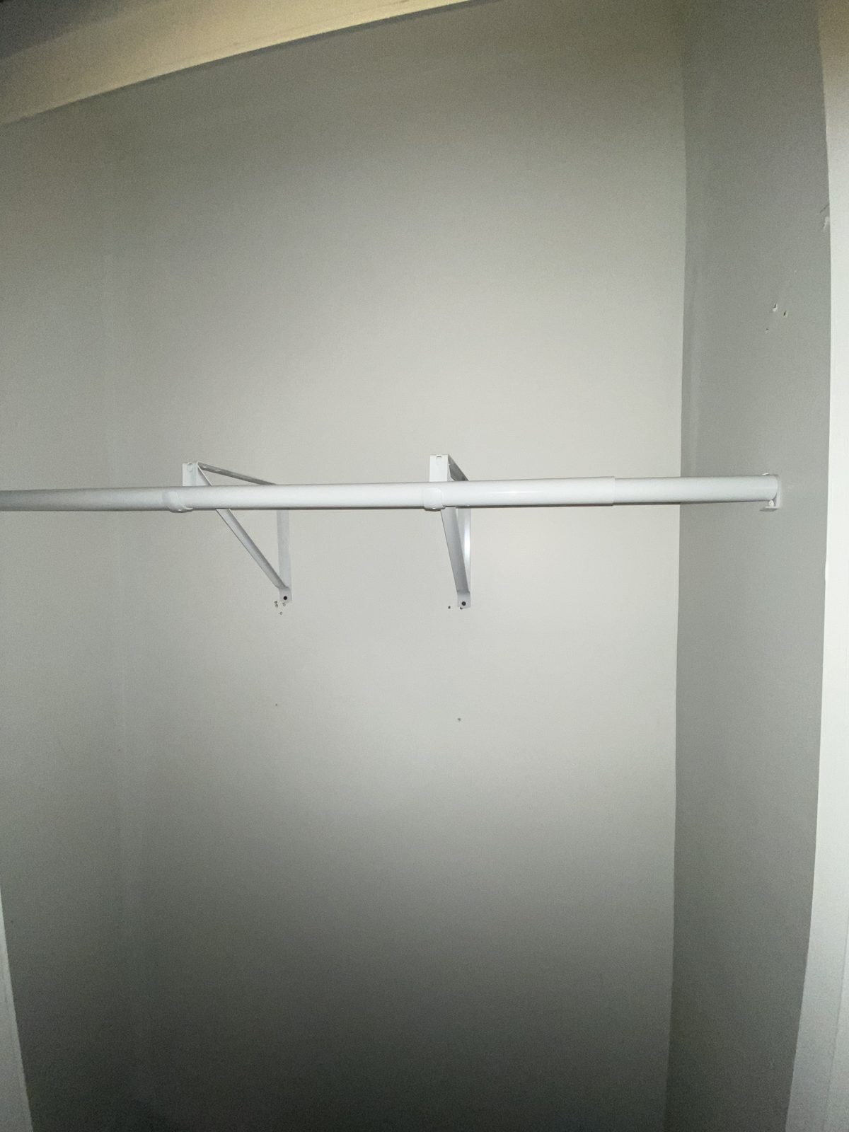 Newly installed white closet rod with mounting brackets