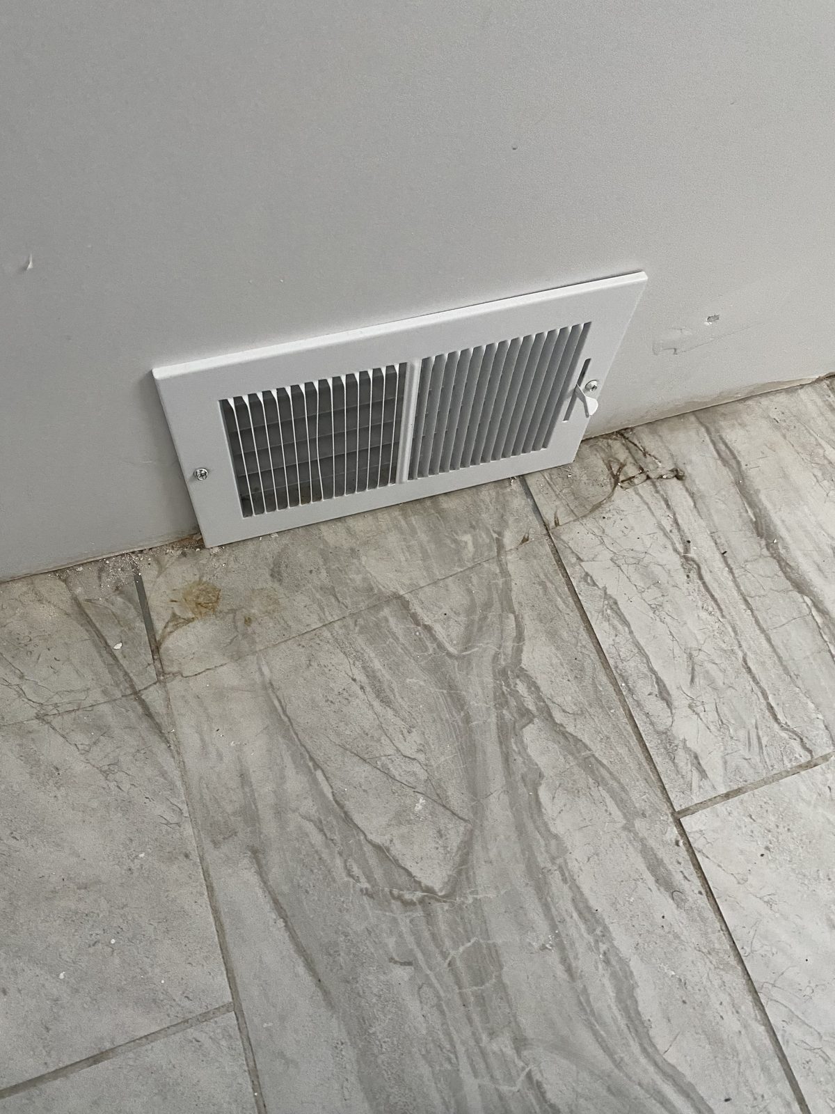 Installed white floor vent cover above tile flooring